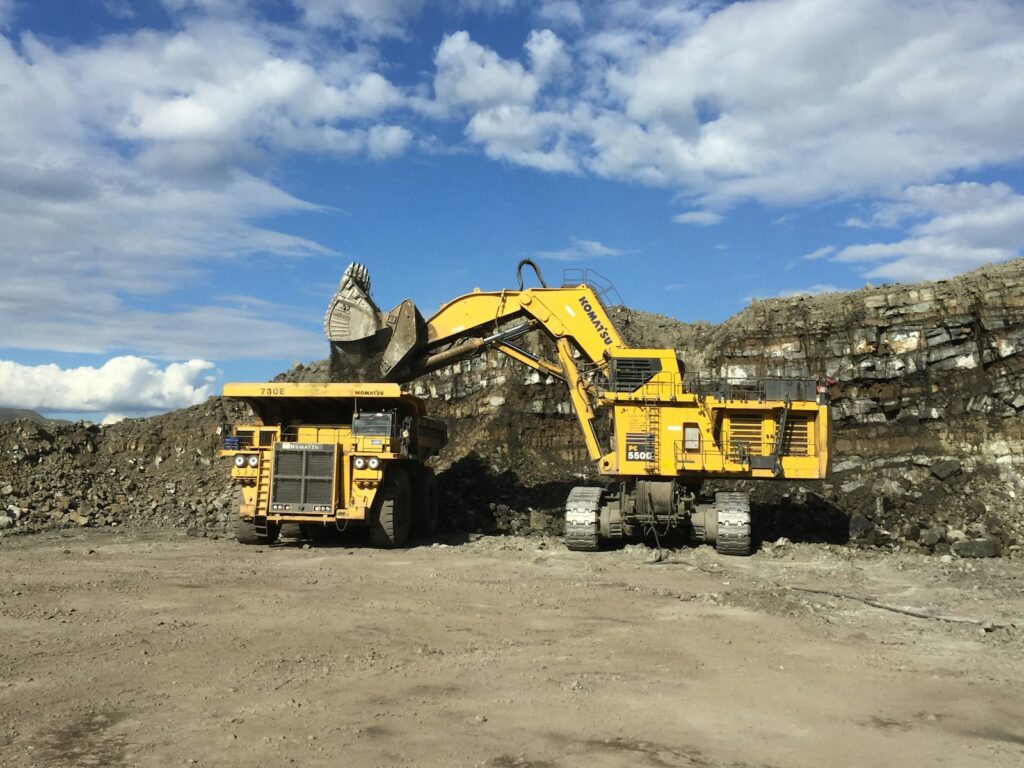 yellow and black heavy equipment on brown sand under blue sky during daytime